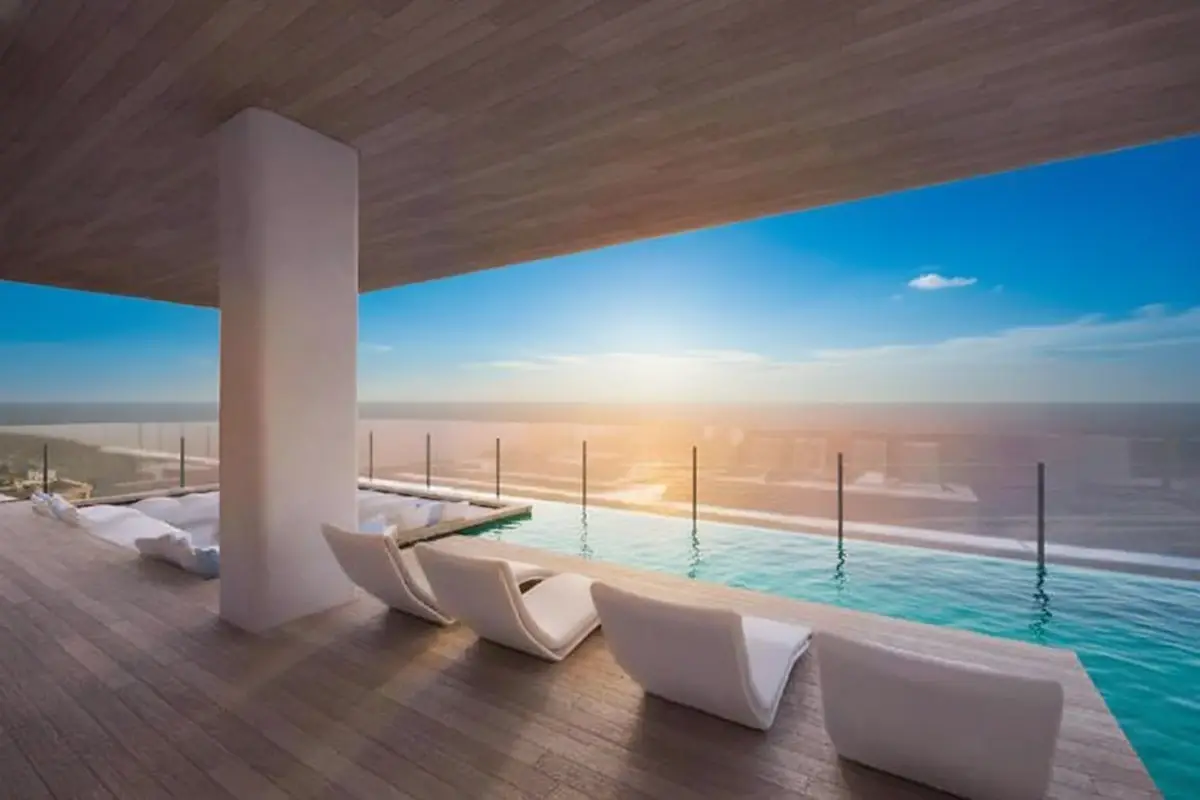 Arom Jomtien rooftop terrace with infinity pool, sun loungers, and ocean sunset view.
