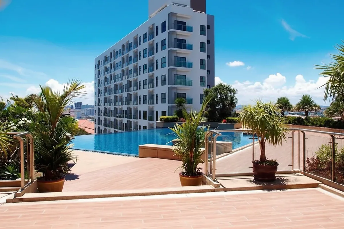 Axis Pattaya Condo exterior view of the modern building with green facade and lush tropical landscaping.
