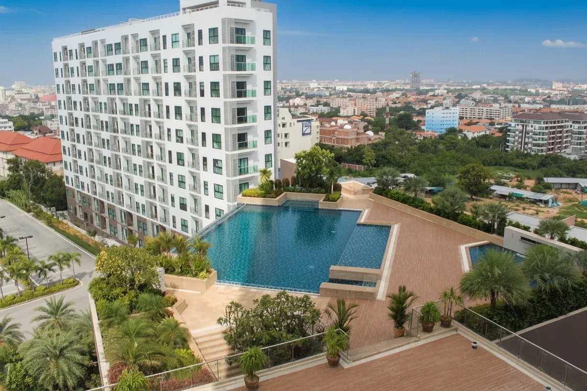 Axis Pattaya Condo infinity pool with a woman and child swimming, overlooking the city skyline.