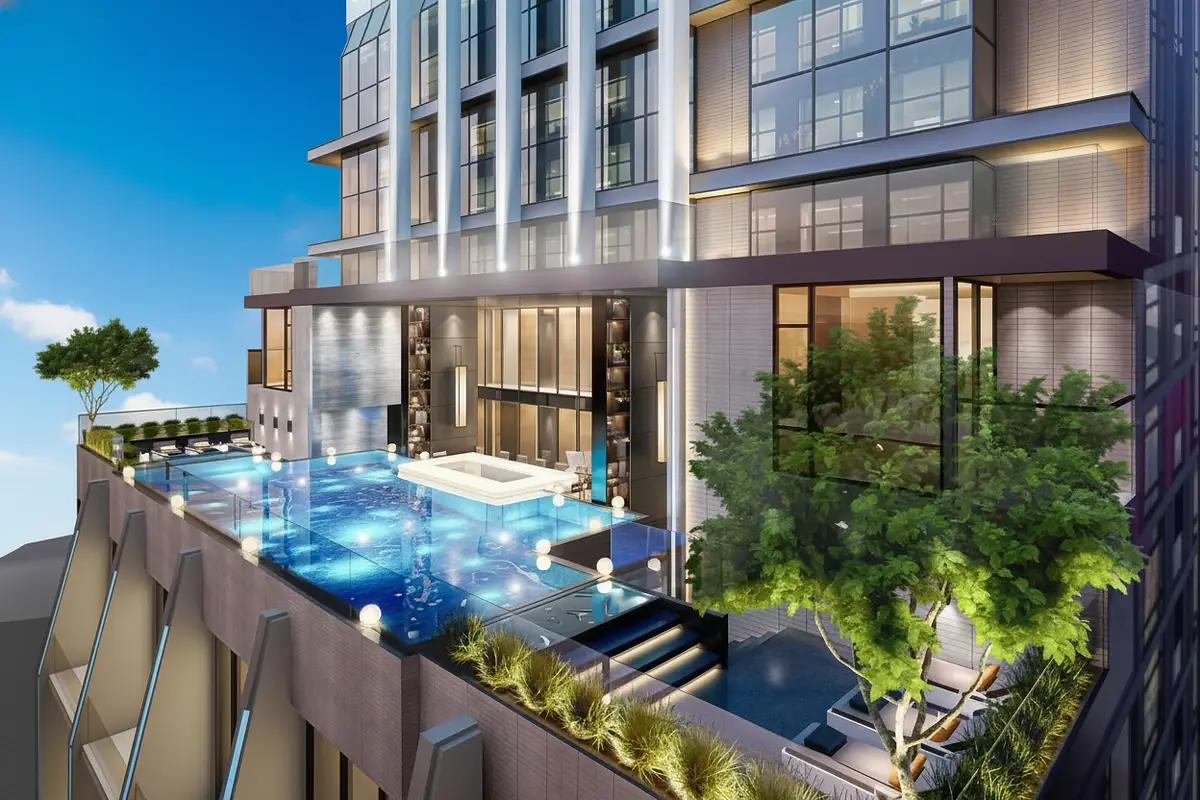 Beverly Mountain Bay Pattaya rooftop pool deck with illuminated blue water, lounge seating, and modern building facade at dusk.