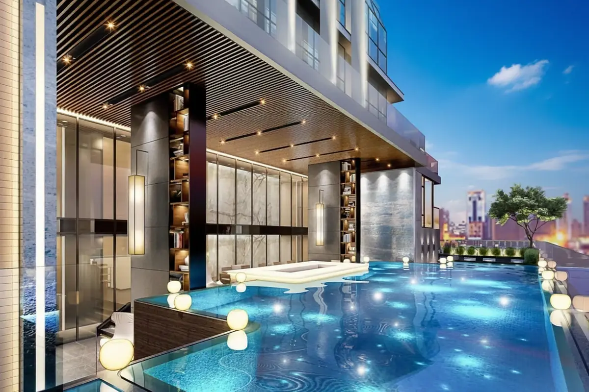 Beverly Mountain Bay Pattaya close-up of the rooftop pool with glowing lights, a white jacuzzi, and a stylish building entrance.