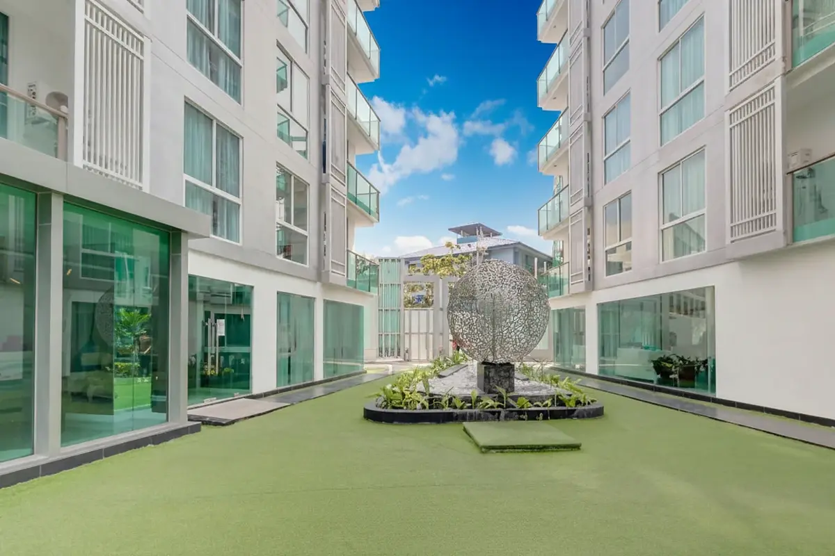 City Center Residence rooftop garden area with artificial turf, a decorative sculpture, and buildings.