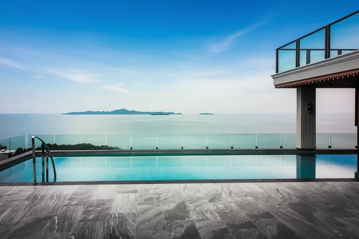 Elysium Residences infinity pool overlooking the ocean and distant islands under a blue sky.