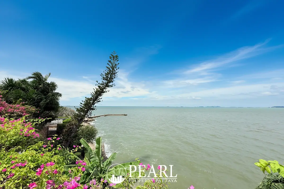 Garden Cliff Condominium 1 scenic pathway leading to a white gate with ocean views and tropical trees.