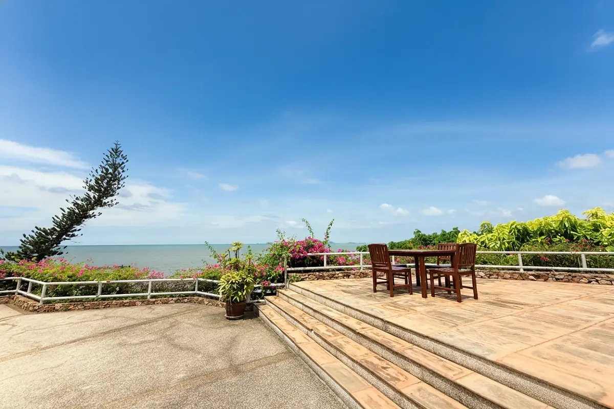 Garden Cliff Condominium 1 expansive outdoor swimming pool with a covered seating area and ocean in the background.