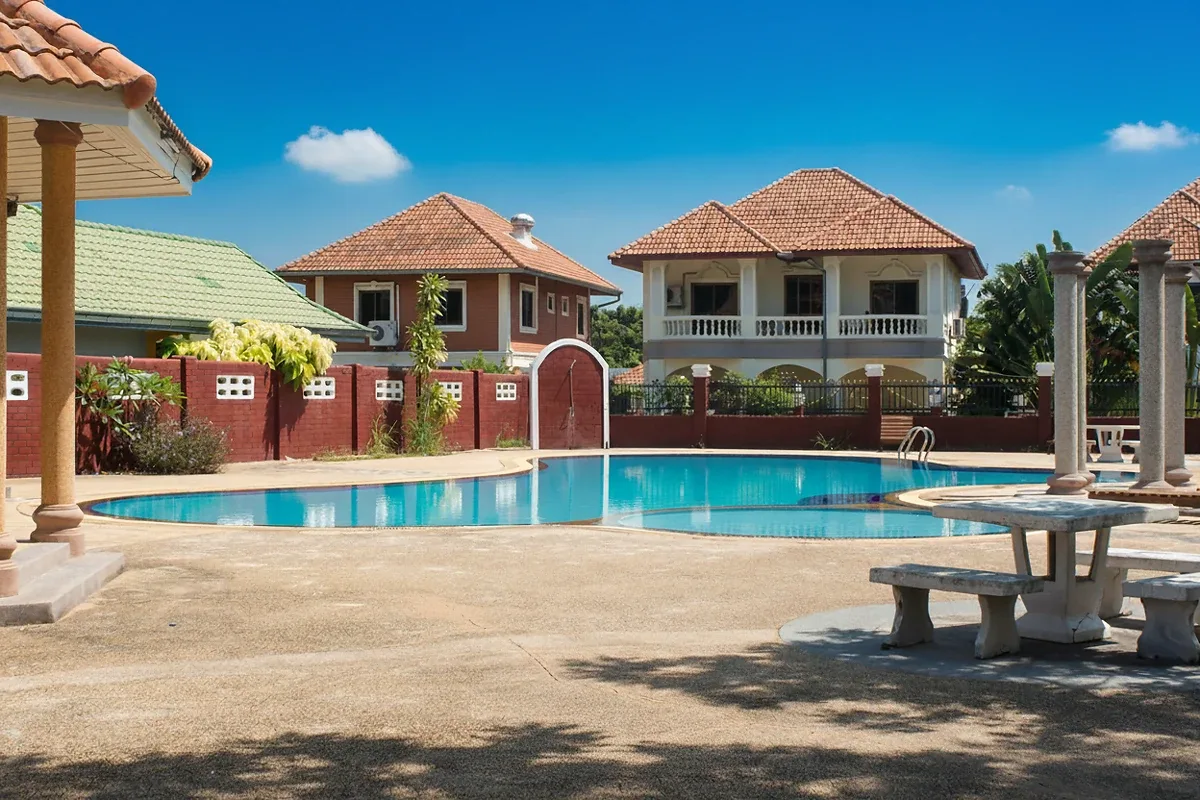 Grand Tanyawan Home large community swimming pool with houses and blue sky in the background.