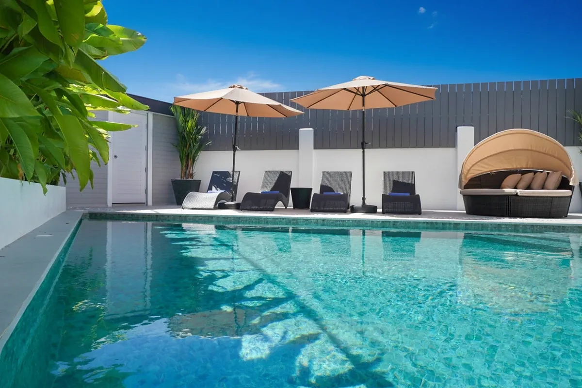Grand Tanyawan Home large community swimming pool with houses and blue sky in the background.