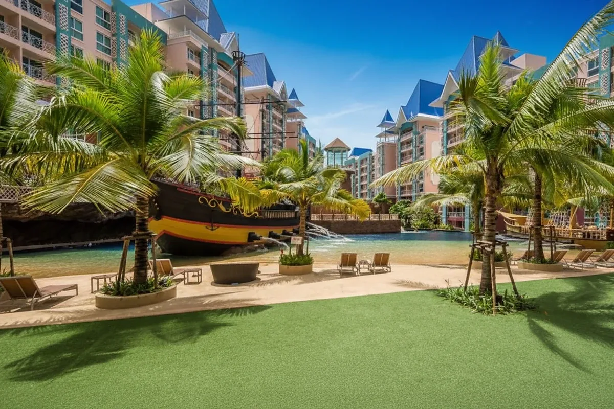 Grande Caribbean resort pool area with a pirate ship, artificial beach, palm trees, and residential buildings.