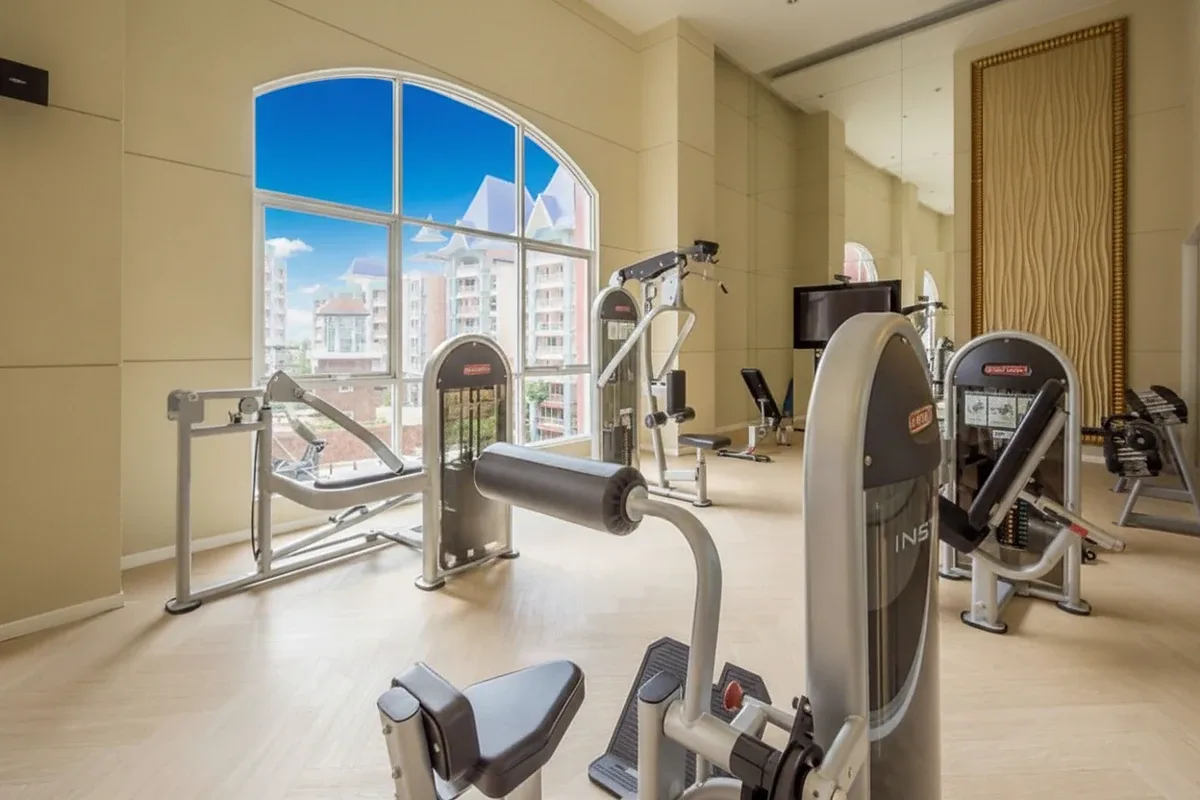 Grande Caribbean fitness center with various exercise machines, large arched window, and city views.