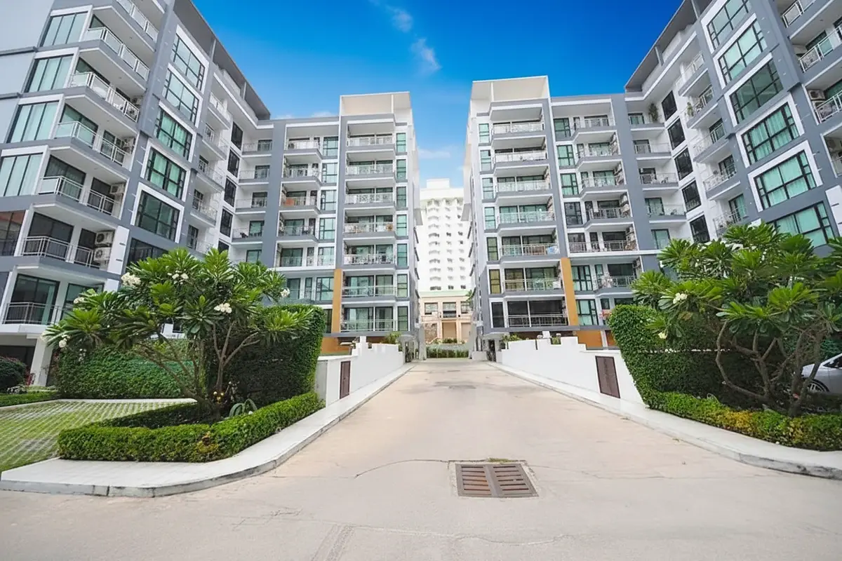 Neo Condo exterior view of two modern buildings with balconies flanking a central driveway entrance.