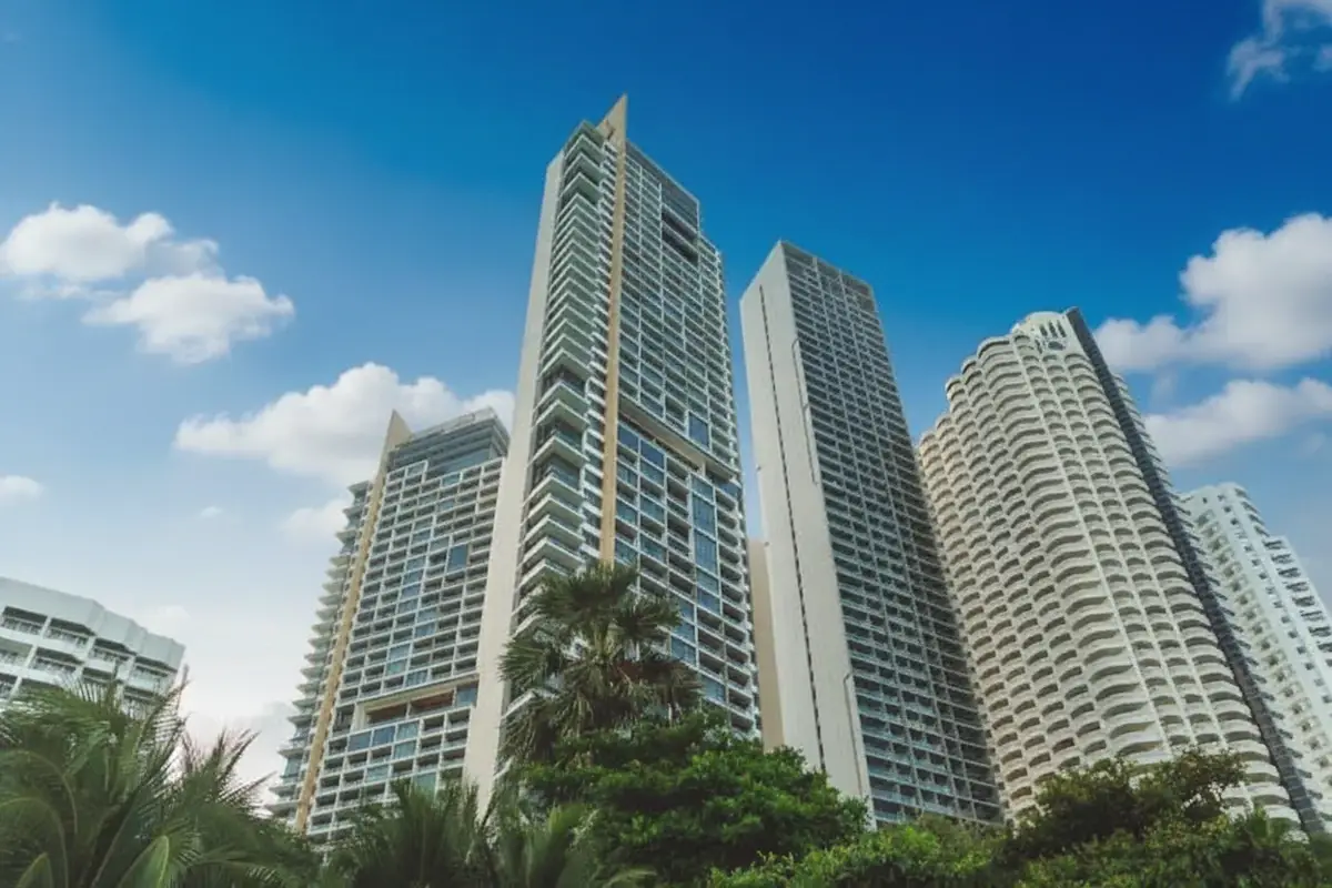 Northpoint tall modern condo buildings with lush green trees against a blue sky in Pattaya, Thailand.