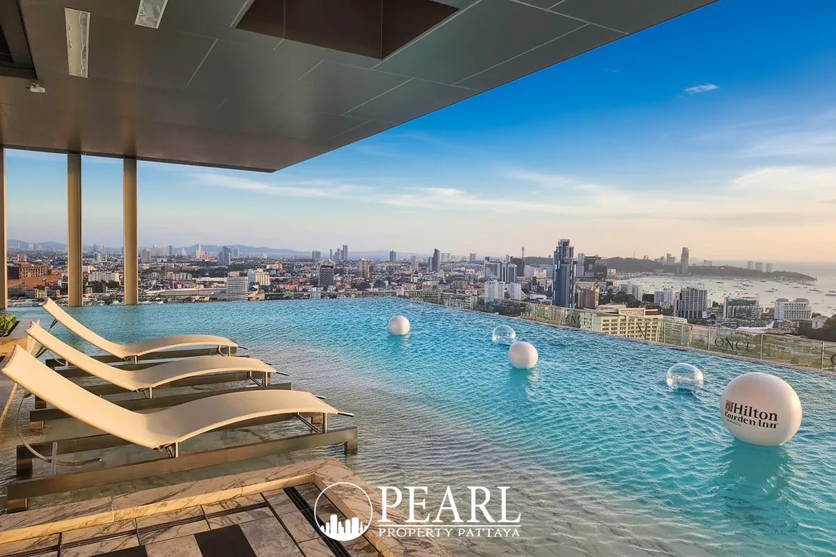 Once Pattaya rooftop infinity pool with lounge chairs overlooking the Pattaya city skyline and ocean.