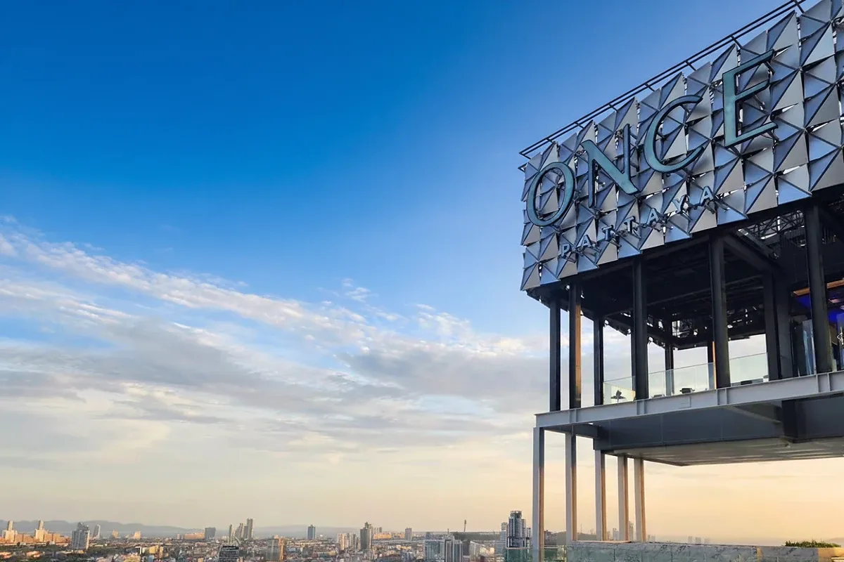 Once Pattaya rooftop sign for the condo building against a bright blue sky with scattered clouds.