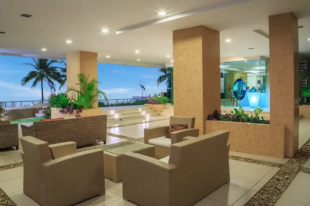 Paradise Ocean View: Outdoor lounge area with wicker furniture, potted plants, and illuminated steps at night.