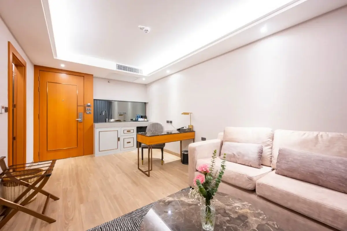 1 Bedroom Condo for Sale at Wyndham Jomtien Pattaya: Living area with sofa, kitchenette, and wooden entrance door.