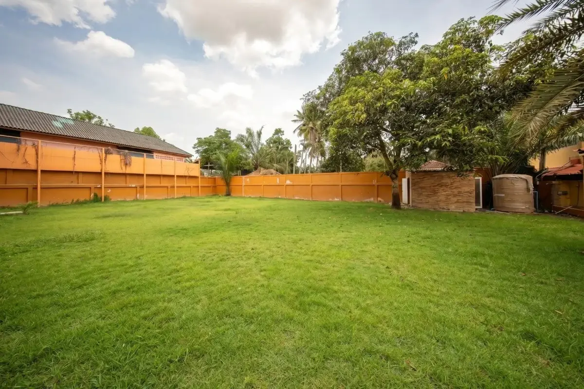 5 Bedroom House for Sale in Huai Yai featuring a large, well-maintained green lawn surrounded by an orange fence.