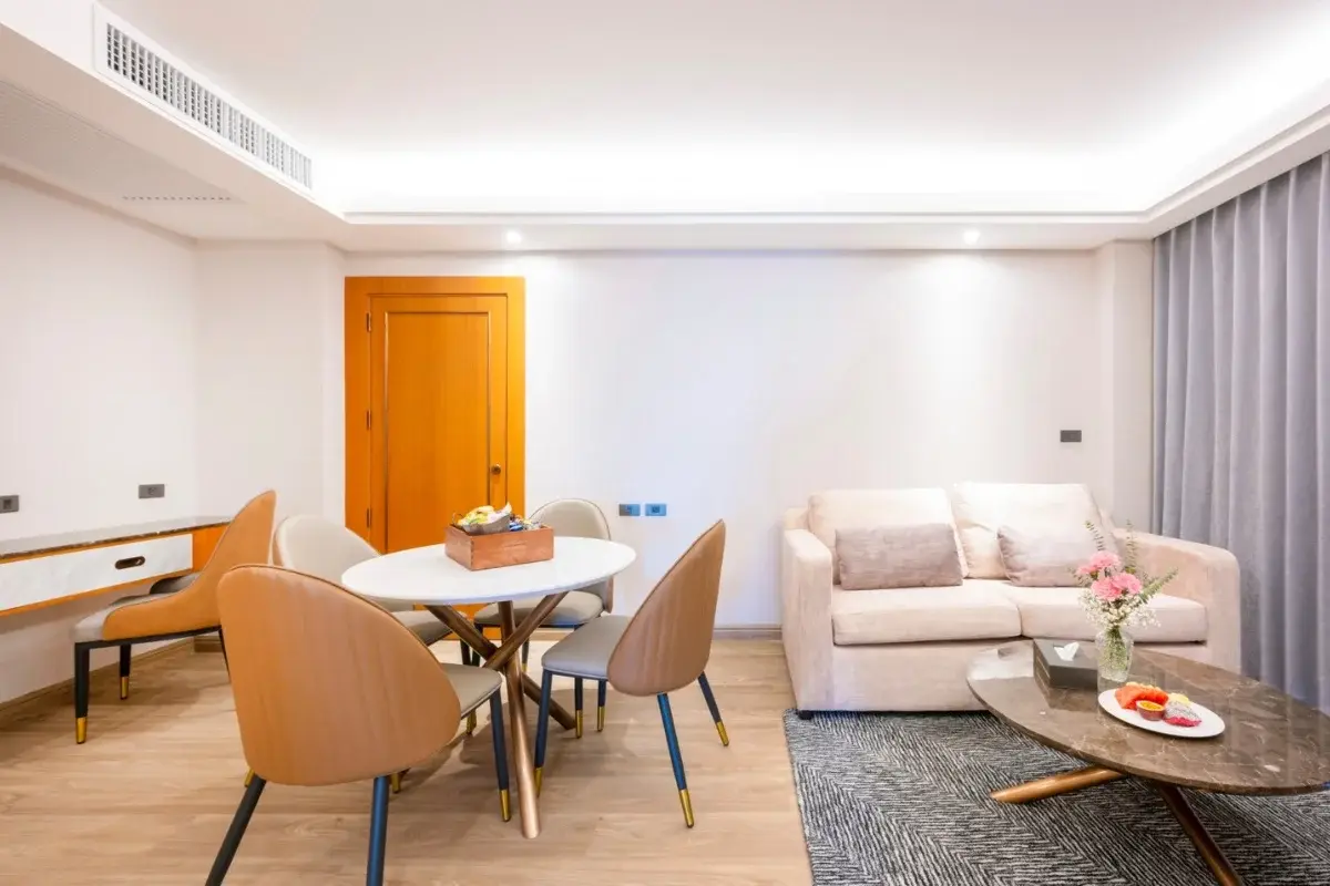 2 Bedroom Condo for Sale at Wyndham Jomtien Pattaya - living room with light sofa, dining table, and wooden door.