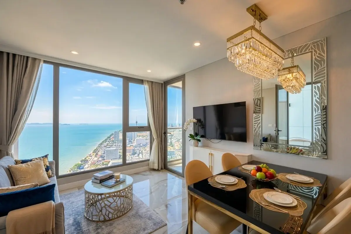 1 Bedroom Condo for Sale at Copacabana Beach Jomtien living room with sofa, dining table, and floor-to-ceiling windows.