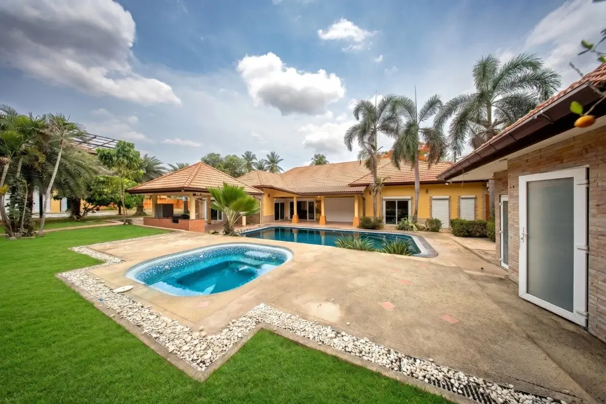 5 Bedroom House for Sale in Huai Yai with a main pool, smaller jacuzzi, and expansive green lawn area.