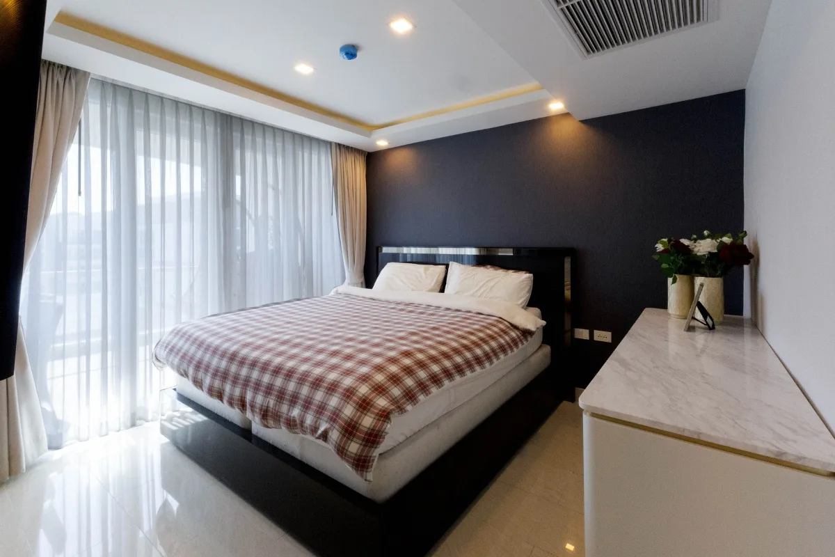 2 Bedroom Condo for Sale at Grand Avenue Residence: Bedroom with large bed, checkered duvet, and sheer curtains.