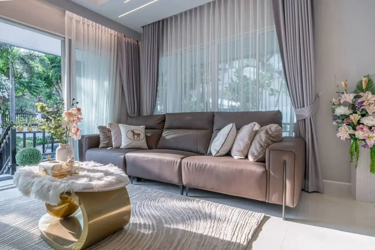 5 Bedroom House for Sale at Central Park 4. Modern living room with a brown sofa, coffee table, and large windows.