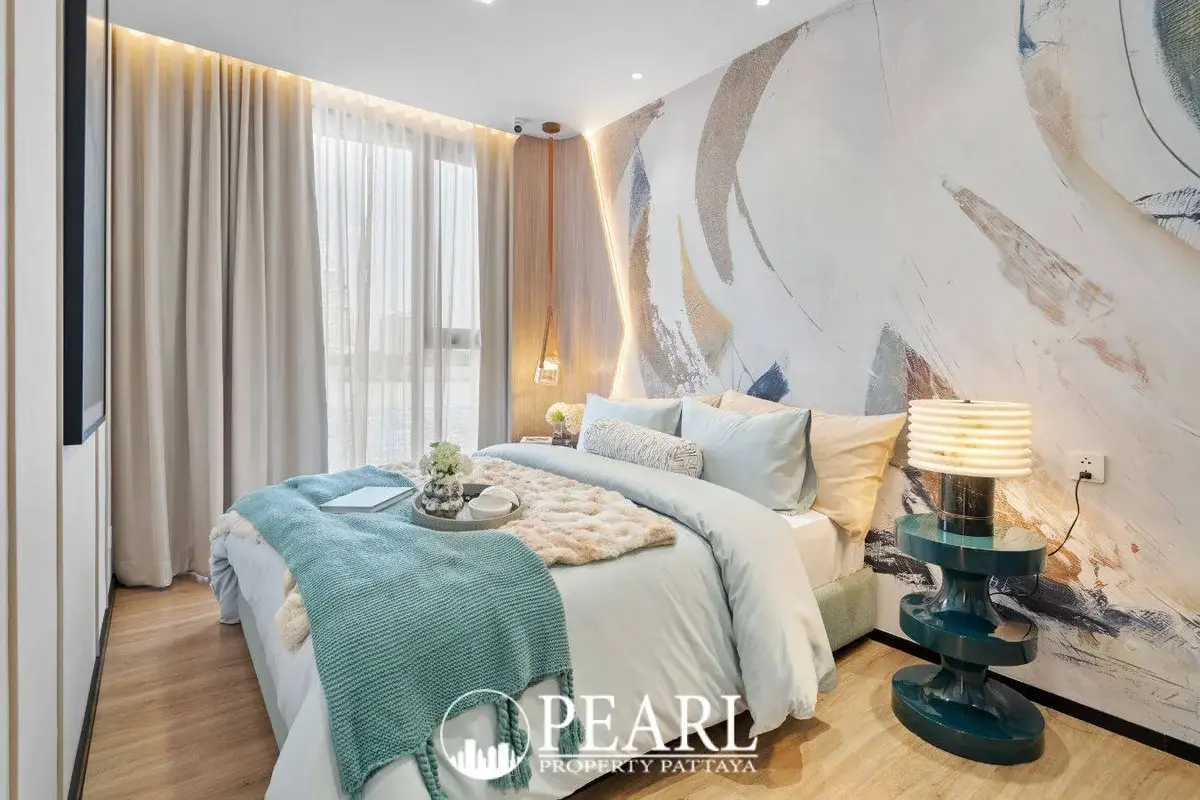 2 Bedroom Grand Executive Condo for Sale at Aquarous Jomtien Pattaya: Stylish bedroom with large bed, artistic wall, and floor-to-ceiling windows.