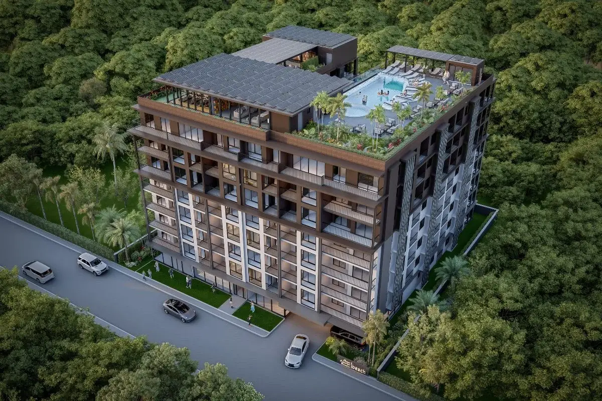 Siam Oriental Beach aerial view of the condo building surrounded by trees, showing the rooftop pool and lounge.