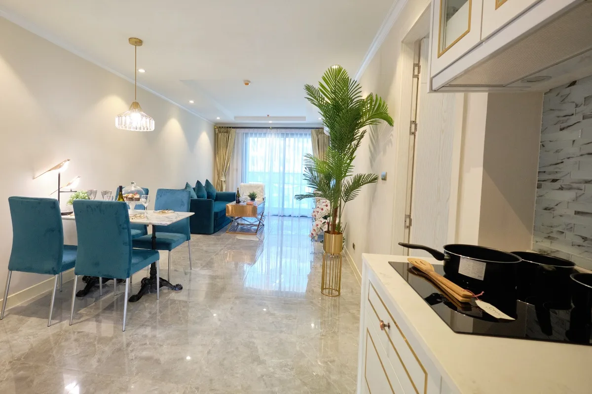 2 Bedroom Condo for Sale at Seven Seas Le Carnival living room with blue sofa, dining table, and balcony access.