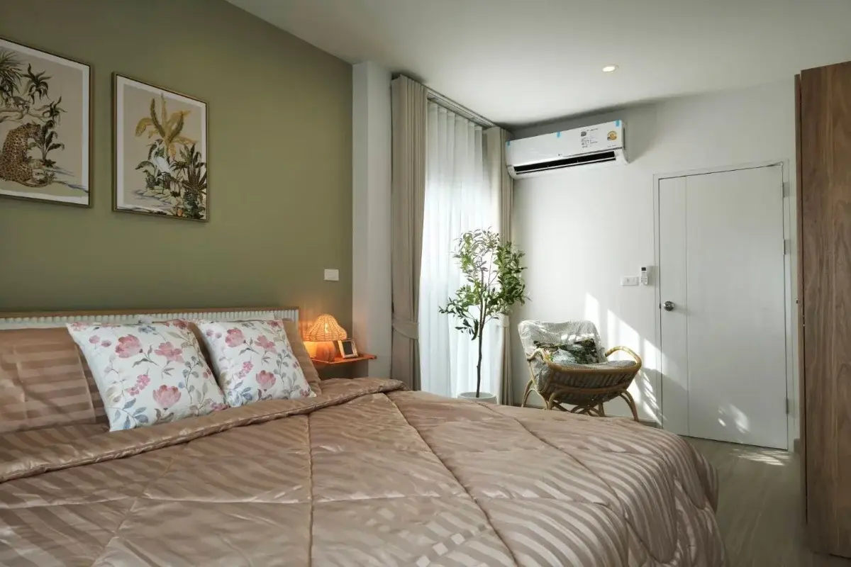 4 Bedroom House for Rent at Supalai Palm Ville Sukhumvit - Rongpo - bedroom with a large bed, green accent wall, and rattan chair.