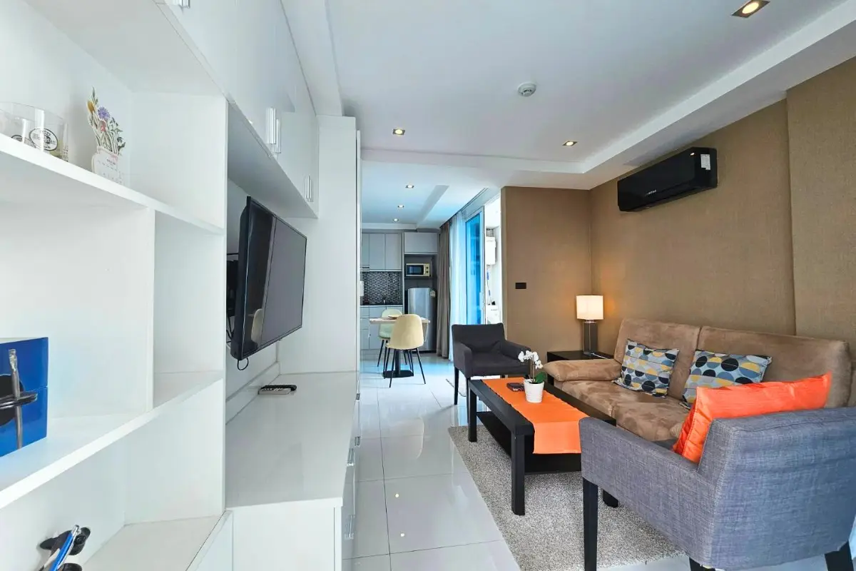 1 Bedroom Condo for Sale & Rent at Serenity Wongamat with TV unit, living room, and kitchen in background.