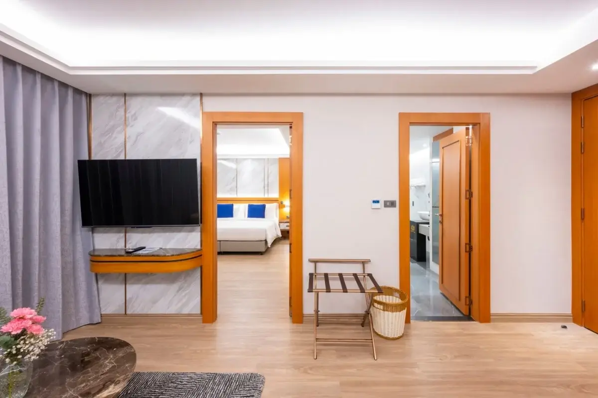 1 Bedroom Condo for Sale at Wyndham Jomtien Pattaya: Living room with TV, open doors to bedroom and bathroom.