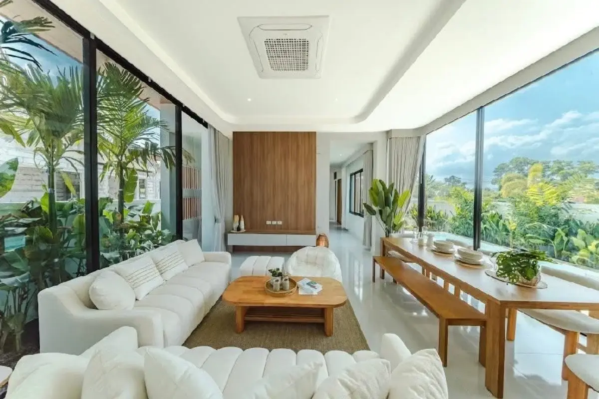4 Bedroom House for Sale in Bang Lamung with a bright living room, white sofas, wooden dining table, and large windows.