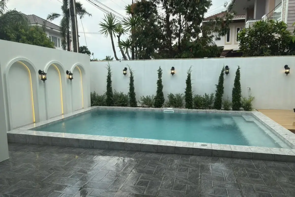 5 Bedroom House for Sale at Baan Suan Lalana, rectangular swimming pool with decorative wall lighting and landscaping.
