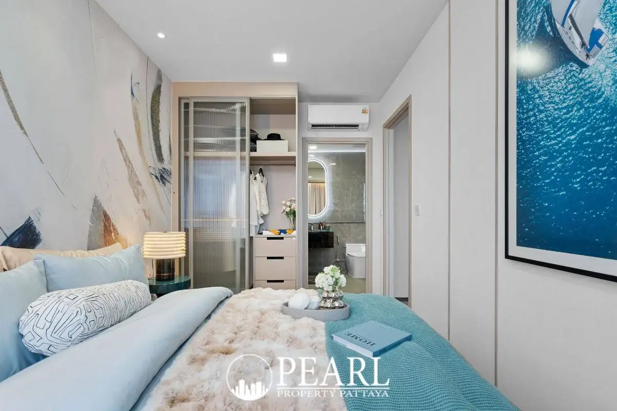2 Bedroom Grand Executive Condo for Sale at Aquarous Jomtien Pattaya: Bedroom with bed, built-in wardrobe, and ensuite bathroom entrance.