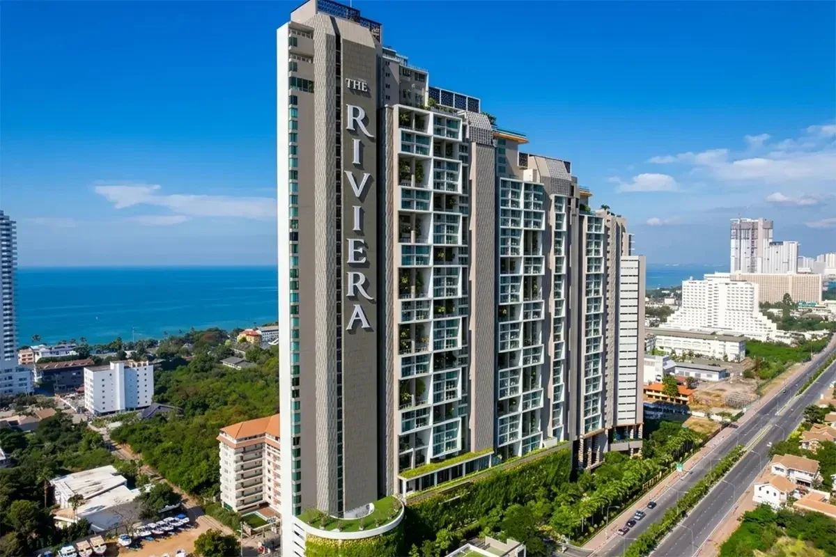 The Riviera Jomtien aerial view of the modern high-rise building with multiple pools and green terraces, overlooking the ocean.