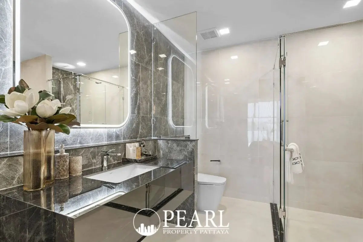 2 Bedroom Grand Executive Condo for Sale at Aquarous Jomtien Pattaya: Bathroom with black marble vanity, illuminated mirror, and shower enclosure.