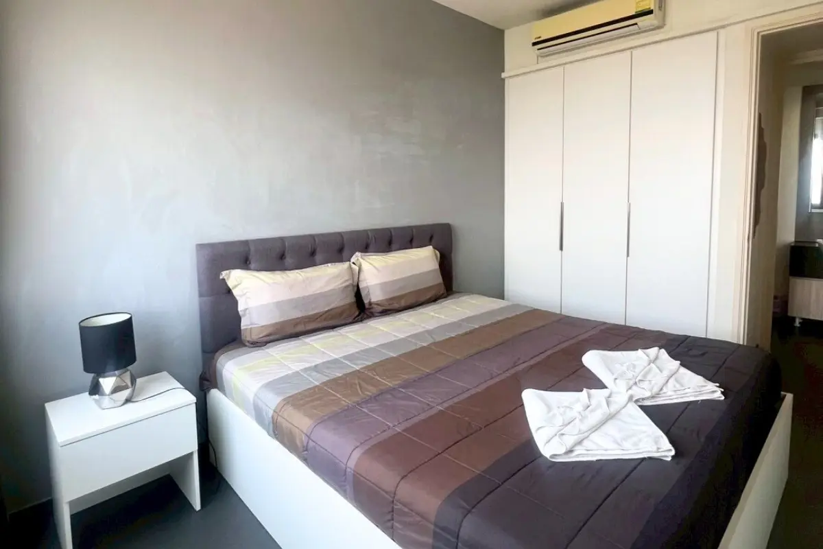 1 Bedroom Condo for Sale at Unixx South Pattaya: bedroom with a large bed, nightstand, lamp, and built-in white wardrobe.