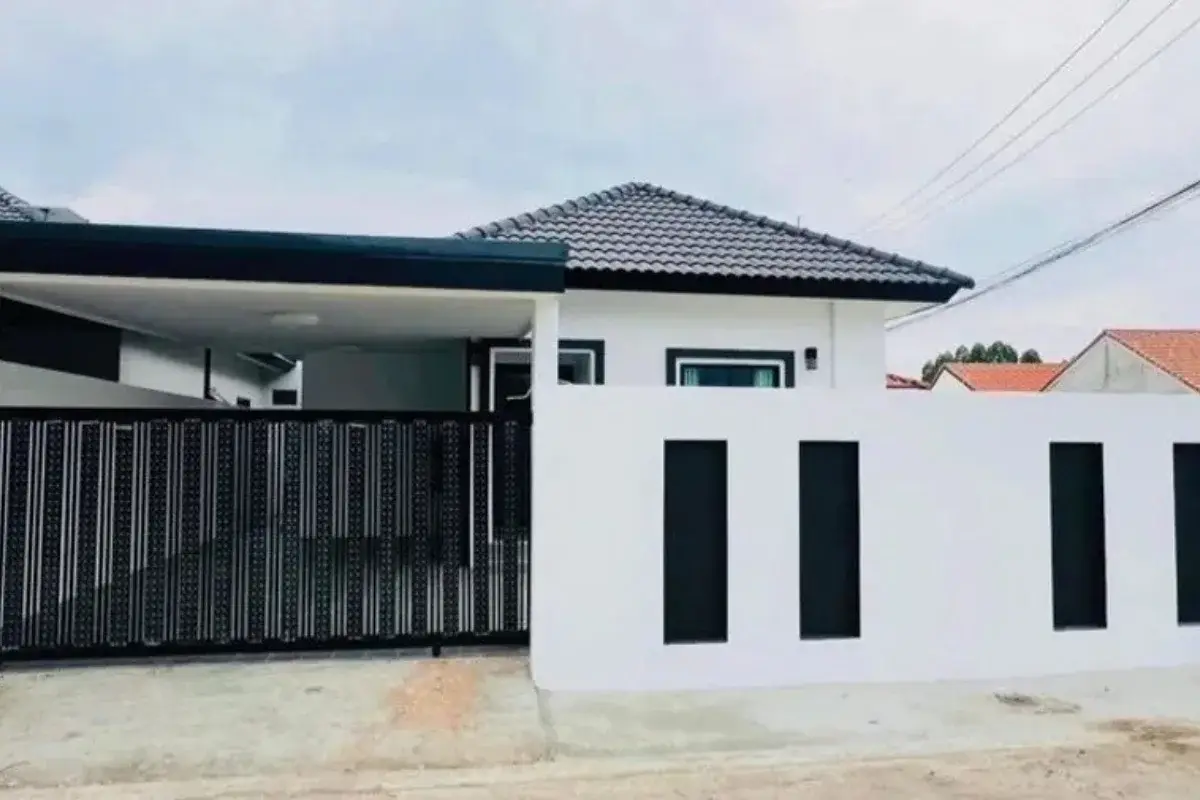 Rattanakorn Village 18 house exterior with a black metal gate, white wall, and covered carport.