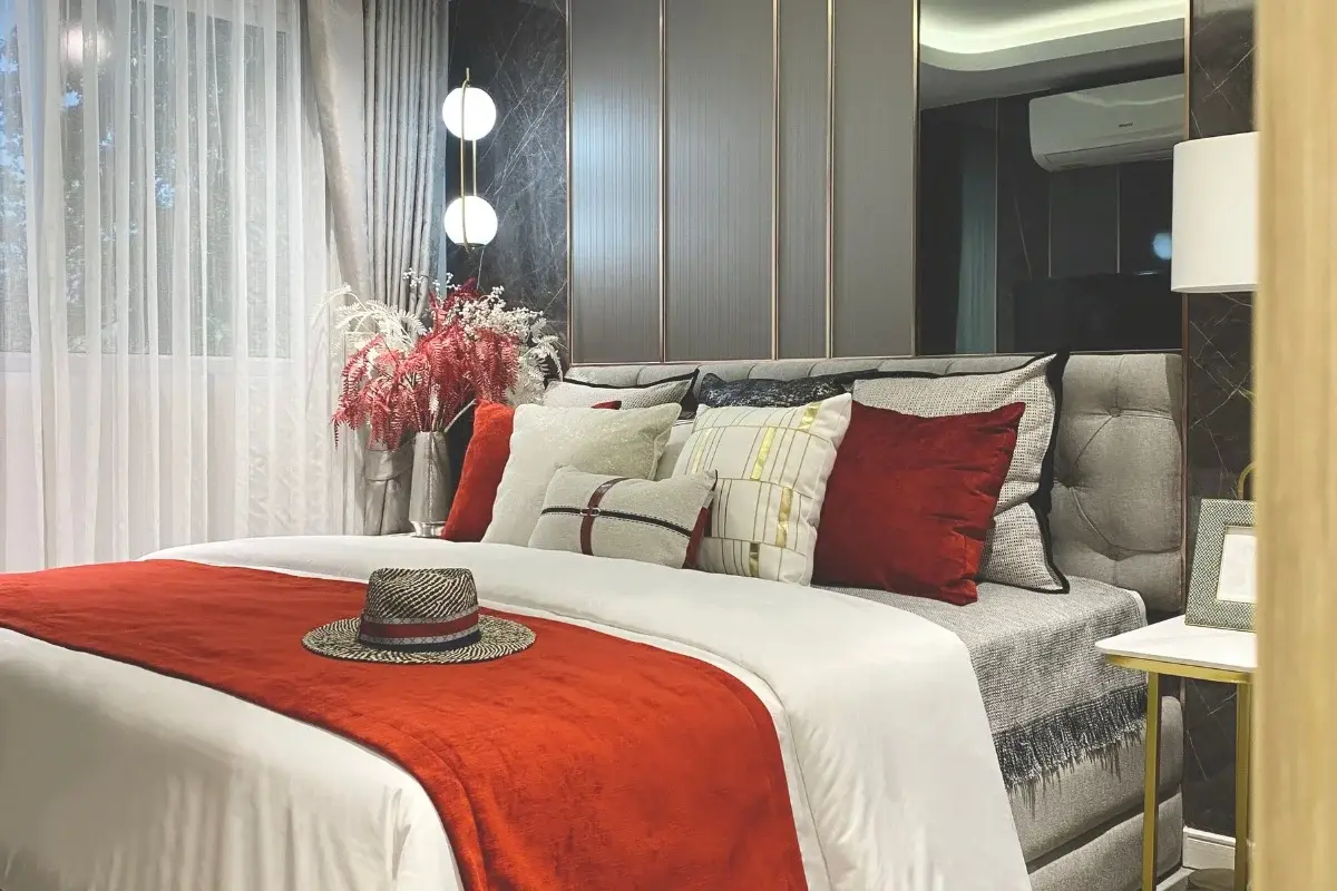 1 Bedroom Condo for Sale at Pristine Park 3, cozy bedroom with large bed, red throw, and decorative pillows.