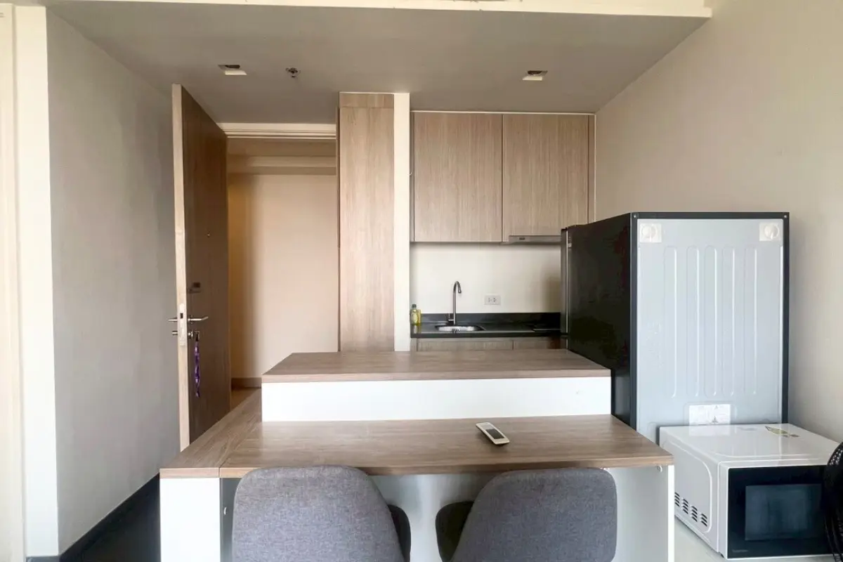 1 Bedroom Condo for Sale at Unixx South Pattaya: kitchen area with wooden cabinets, sink, refrigerator, and dining counter.