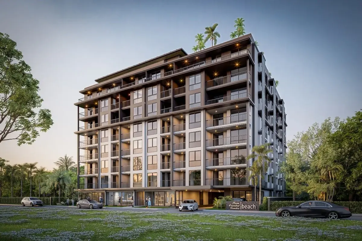 Siam Oriental Beach condo building exterior from a different angle, with cars parked and lush greenery.