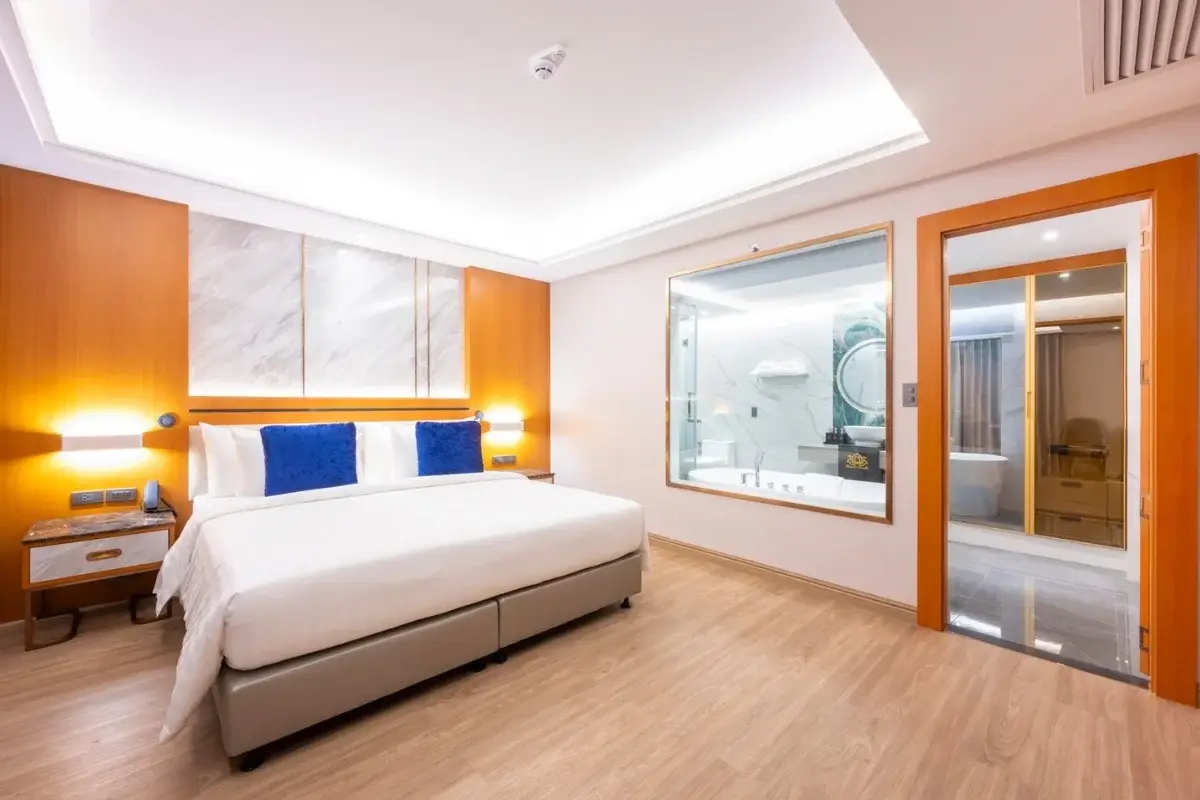 1 Bedroom Condo for Sale at Wyndham Jomtien Pattaya: Bedroom with king-size bed and a glass wall to the bathroom.