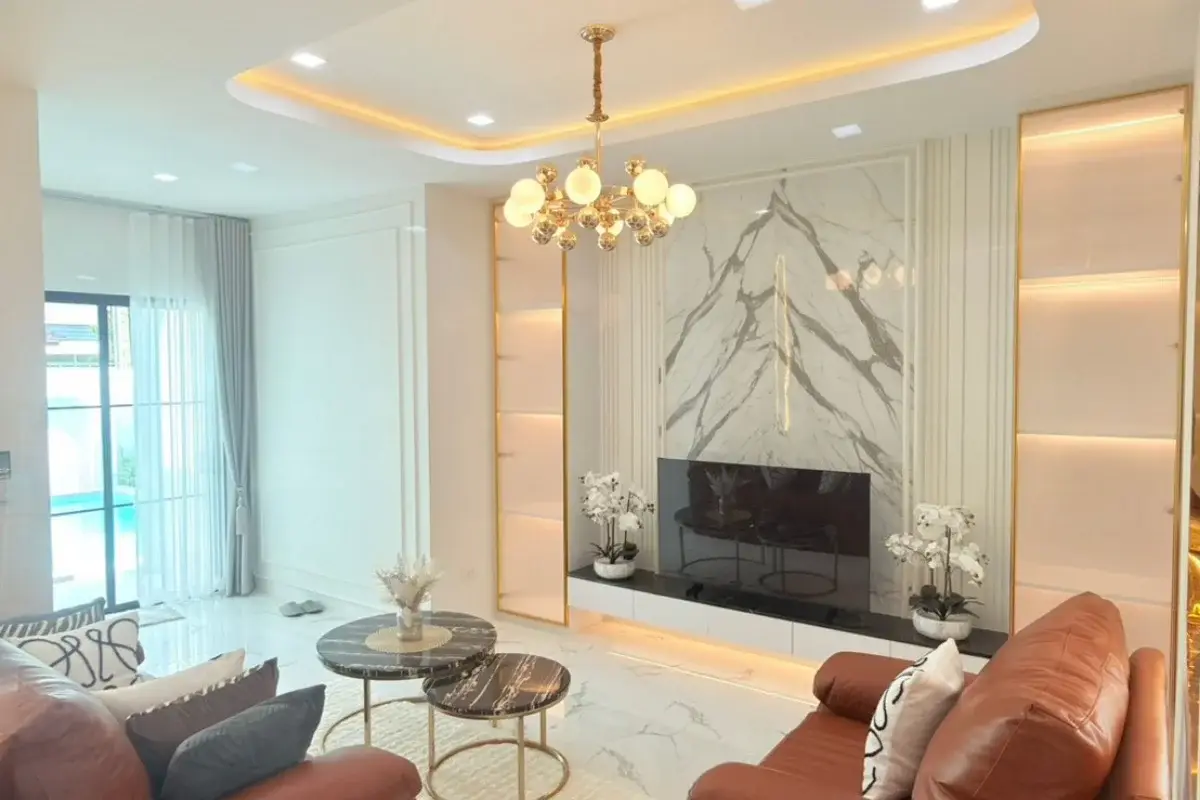 5 Bedroom House for Sale at Baan Suan Lalana, living room with brown sofas, marble TV wall, and chandelier.