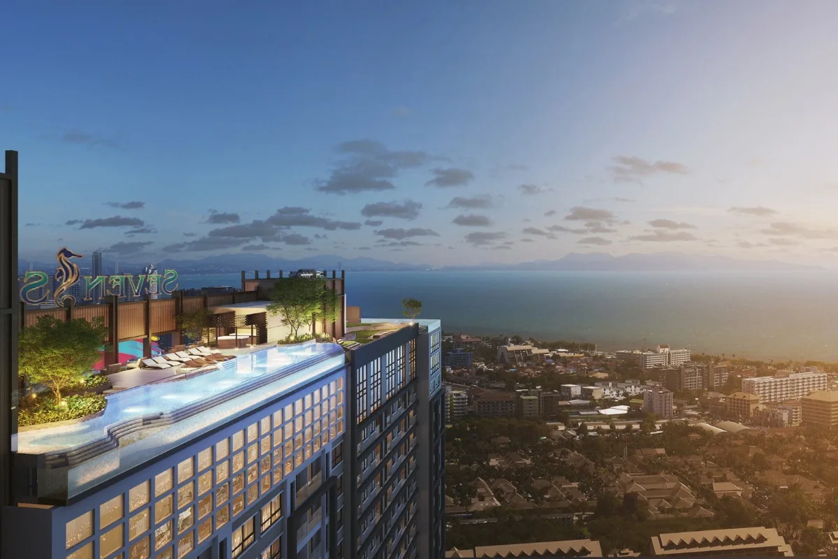 Seven Seas Le Carnival rooftop infinity pool at dusk, with sun loungers and a panoramic view of the ocean and city.