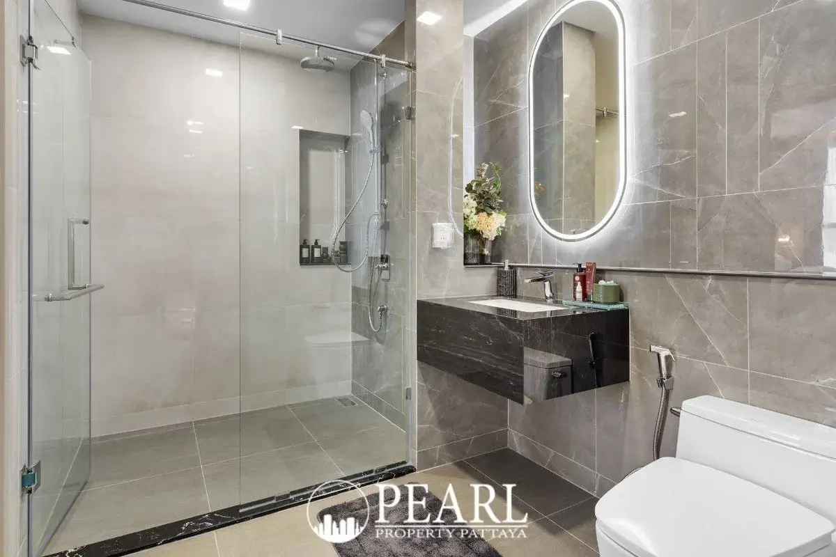 2 Bedroom Grand Executive Condo for Sale at Aquarous Jomtien Pattaya: Modern bathroom with glass shower, floating vanity, and illuminated mirror.