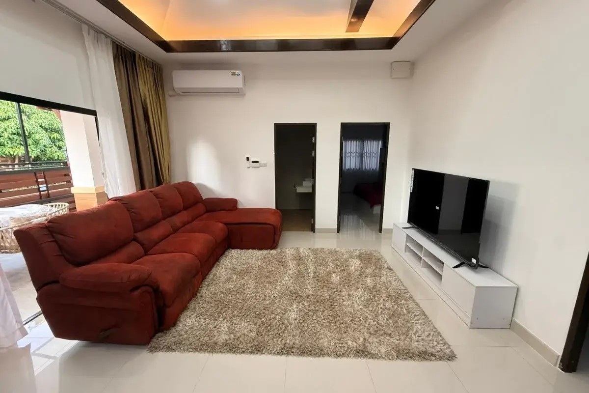 3 Bedroom House for Sale at Baan Dusit Pattaya Park living room with red sectional sofa, TV, and doorways.