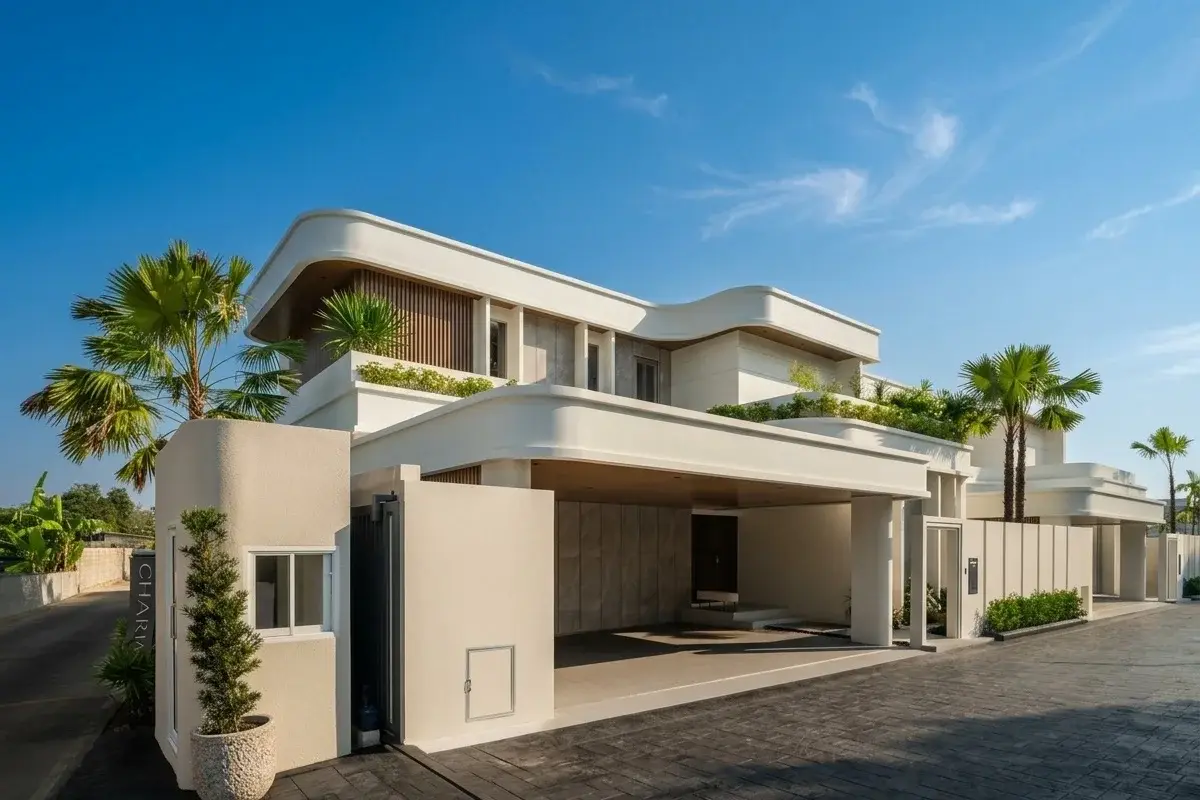 Charin Pattaya aerial view of a row of modern houses with balconies, carports, and a road, surrounded by lush trees.