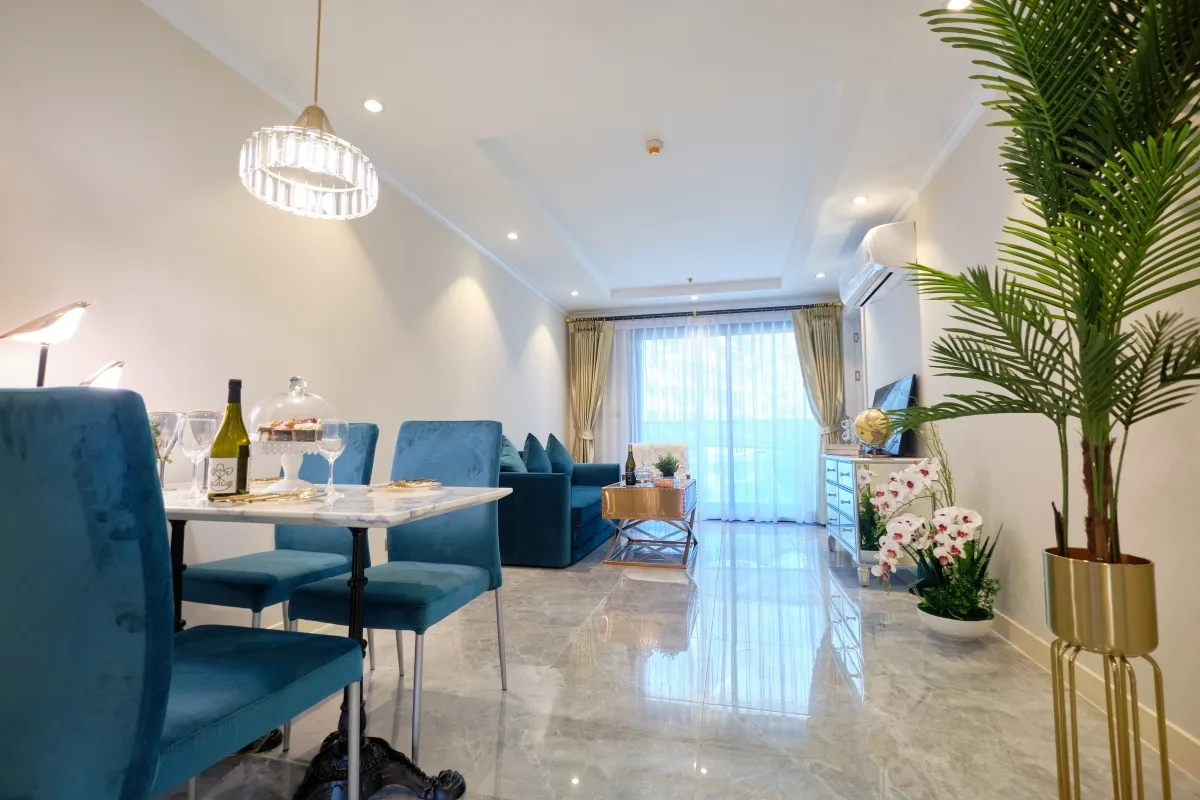 2 Bedroom Condo for Sale at Seven Seas Le Carnival dining area with marble table, blue chairs, and kitchen in background.