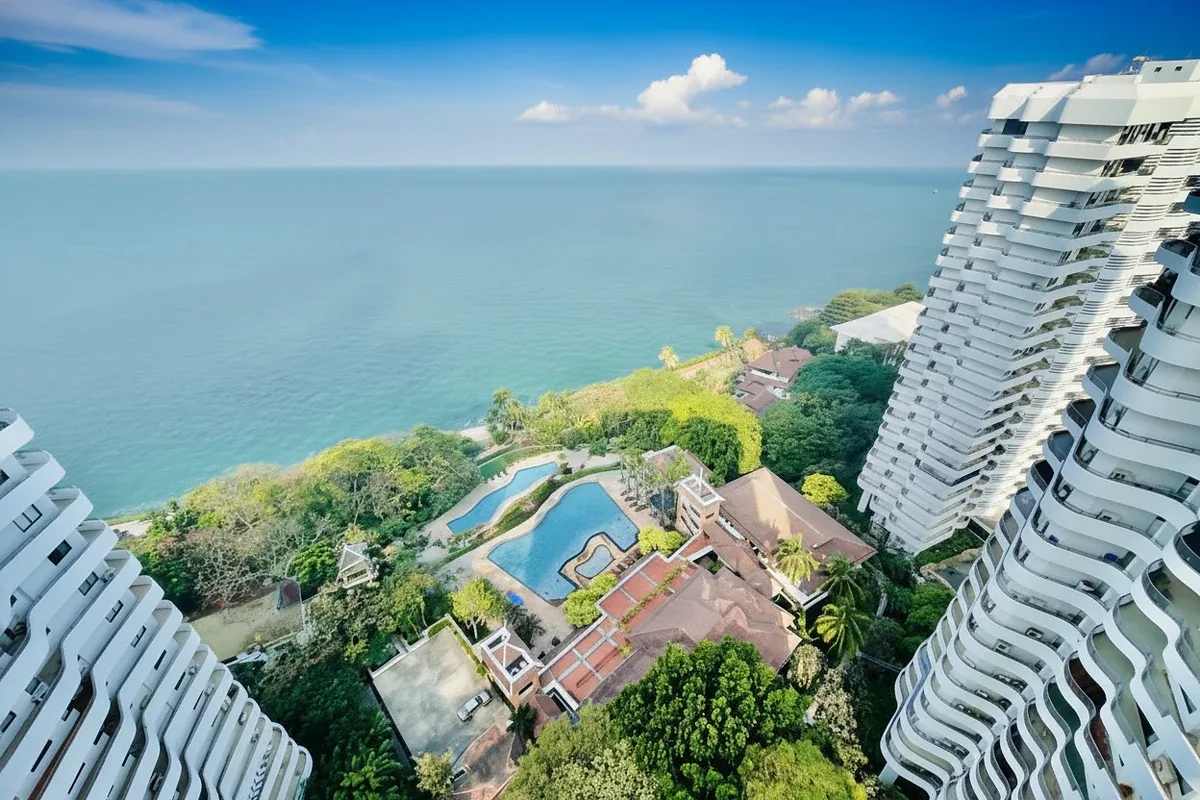 Royal Cliff Garden aerial view of two white condo towers, multiple pools, and lush coastline by the ocean.