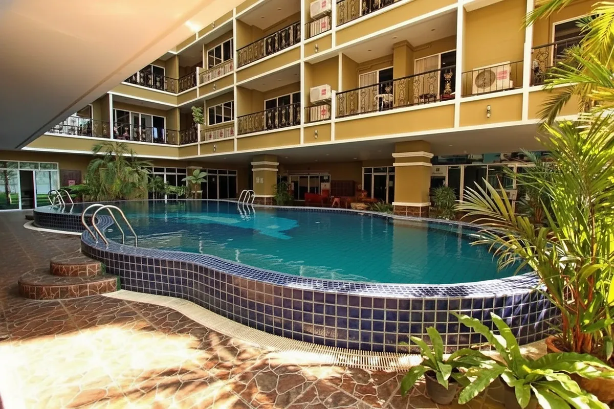 Siam Oriental Twins outdoor swimming pool with blue tiles, surrounded by lush plants and building balconies.